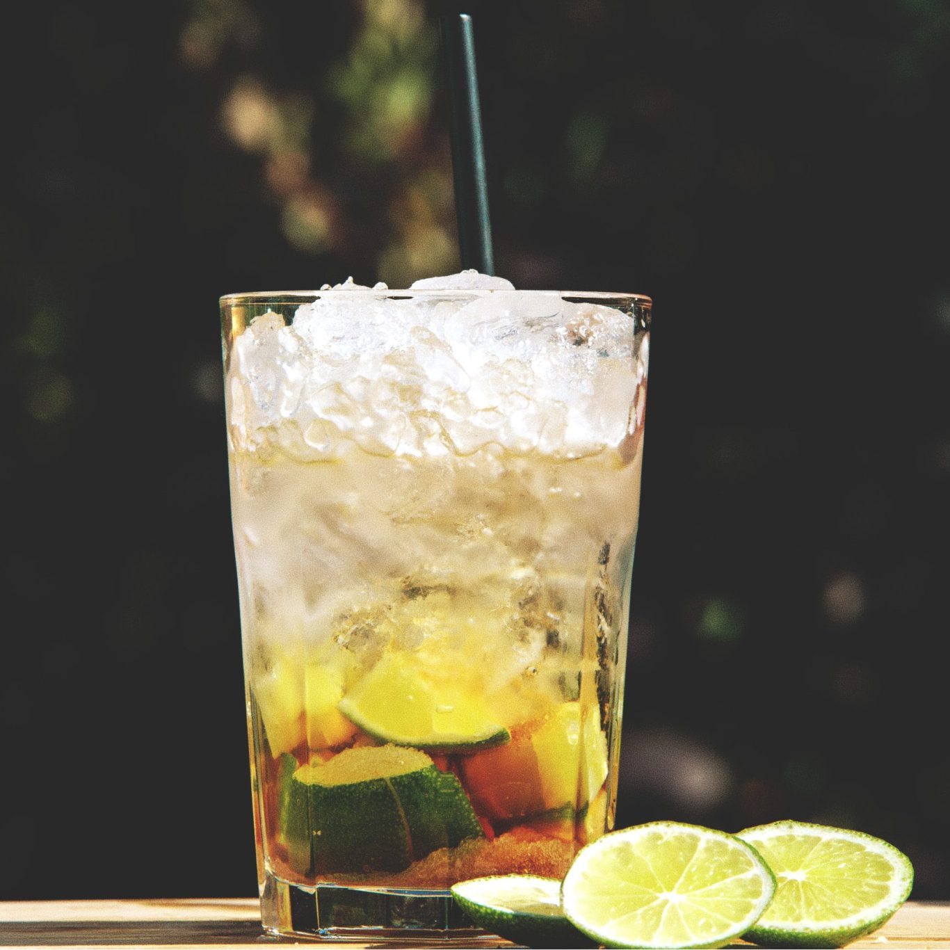 Caipirinha Erfrischendes Getränk mit Limetten und Eis in einem Glas, auf einem Holzuntergrund.